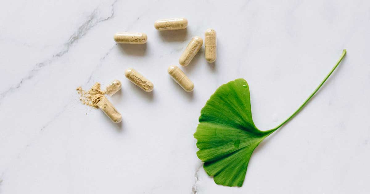 Natural supplement capsules with ginkgo leaf on marble - designer nutritional supplements