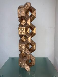 Geometric gold sculpture with interlocking forms displayed as modern statement art