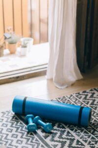 Yoga mat and dumbbells on a home gym floor - simple home workout setup