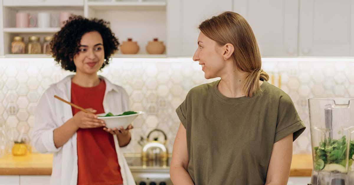 Two women preparing healthy food in a modern kitchen with a blender - everyday healthy cooking