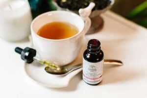 CBD oil drops beside a cup of tea - adding hemp wellness to your daily routine