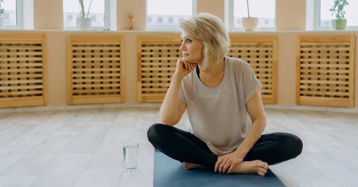 Person sitting on yoga mat in a calm studio setting reflecting and setting personal goals