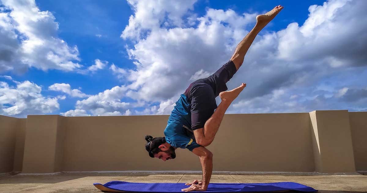 Person performing advanced yoga inversion outdoors showing core strength and balance