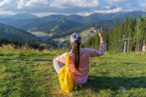 Woman sitting in a mountain meadow enjoying a peaceful view - wellness travel and outdoor restoration